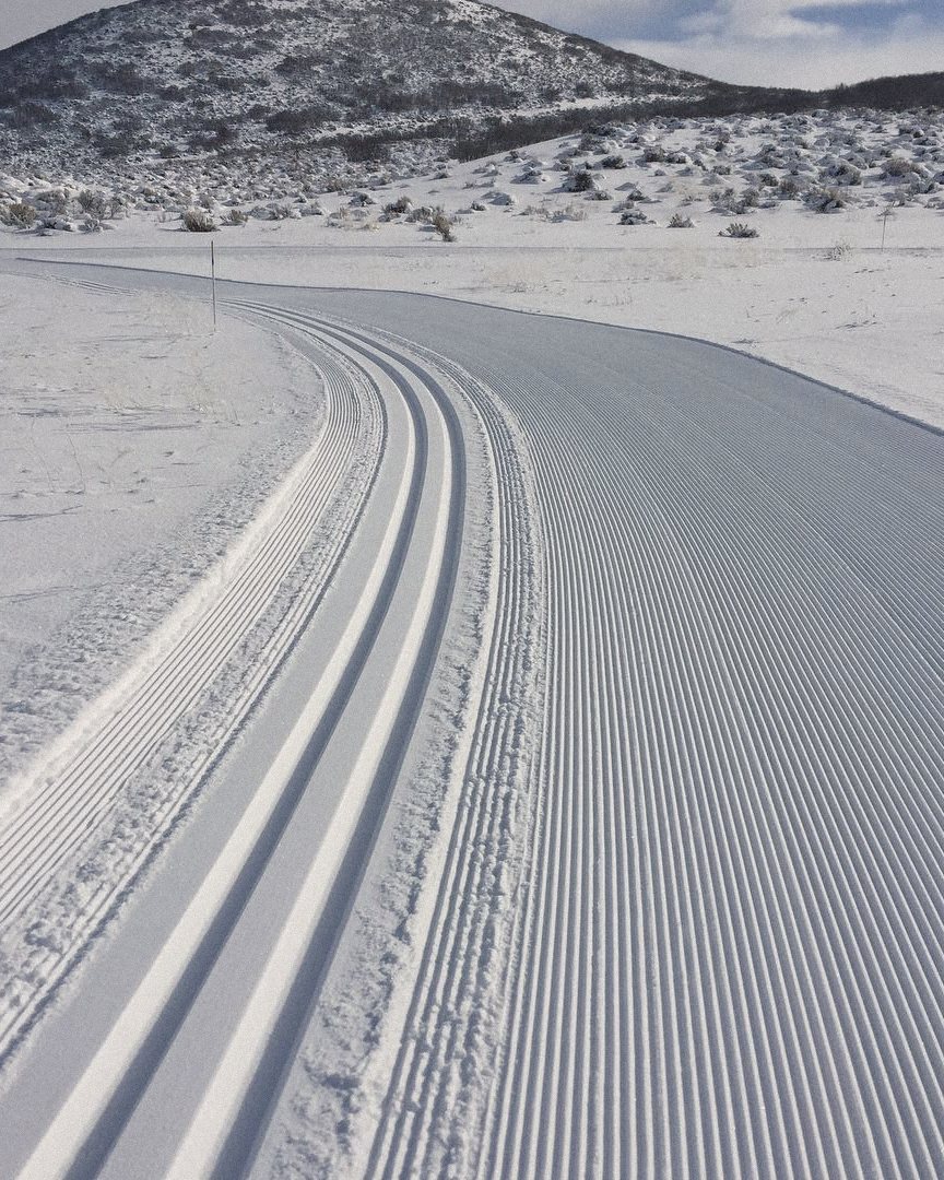 A freshly groomed cross-country ski track with classic tracks set, curving into the distance